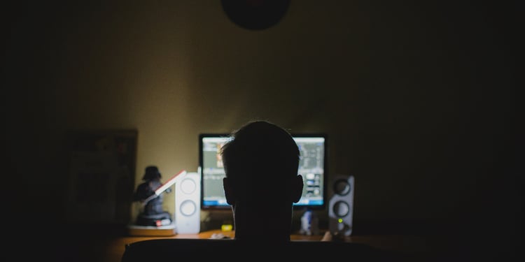 Person that looks like a hacker standing in front of a computer.