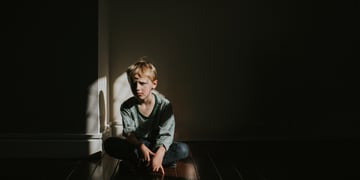 sad kid sitting in the shadows