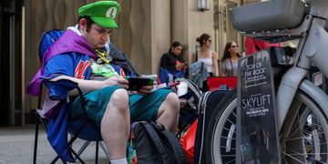 obese man in green super marion hat sitting in chair playing nintendo switch 2