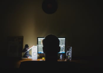 Person that looks like a hacker standing in front of a computer.