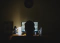 Person that looks like a hacker standing in front of a computer.