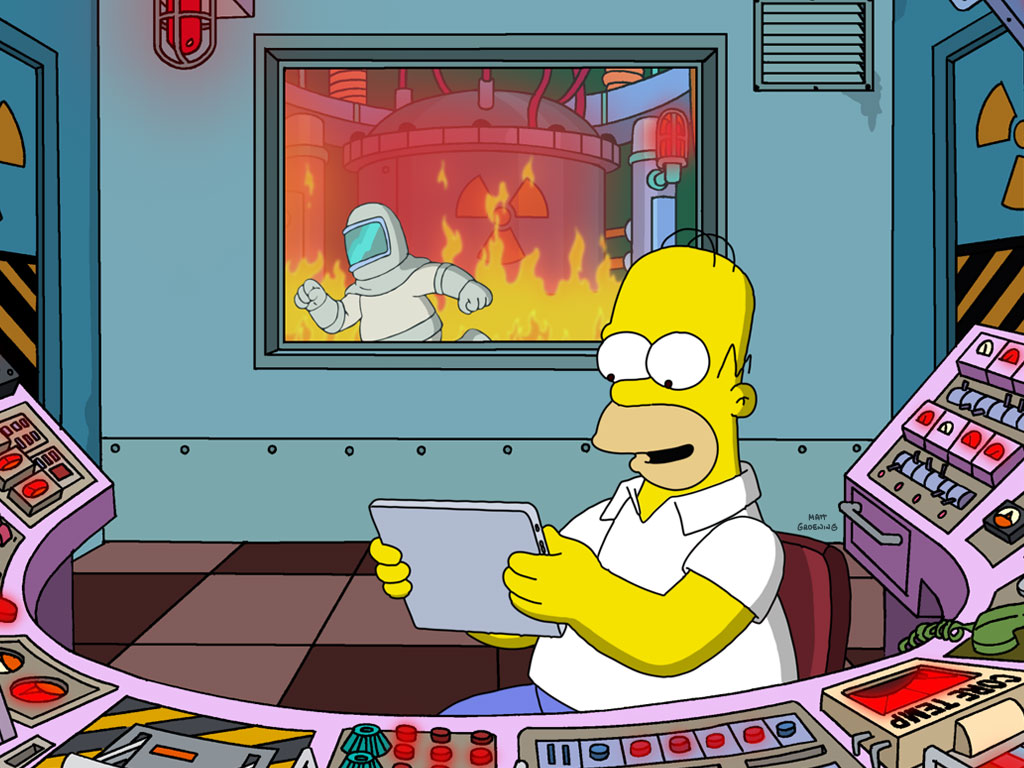 Homer Simpson relaxing & using a tablet, while the factory behind is in flames and being destroyed